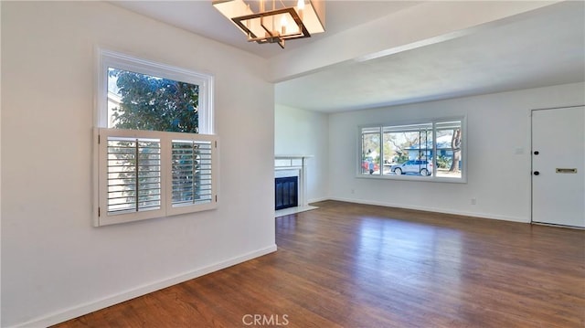 unfurnished living room with dark wood-type flooring and an inviting chandelier