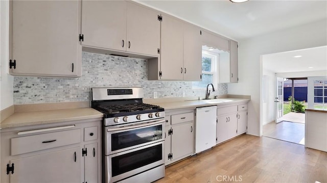 kitchen featuring dishwasher, light hardwood / wood-style floors, double oven range, sink, and white cabinetry