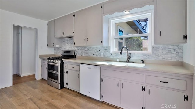 kitchen with white cabinetry, dishwasher, double oven range, and sink