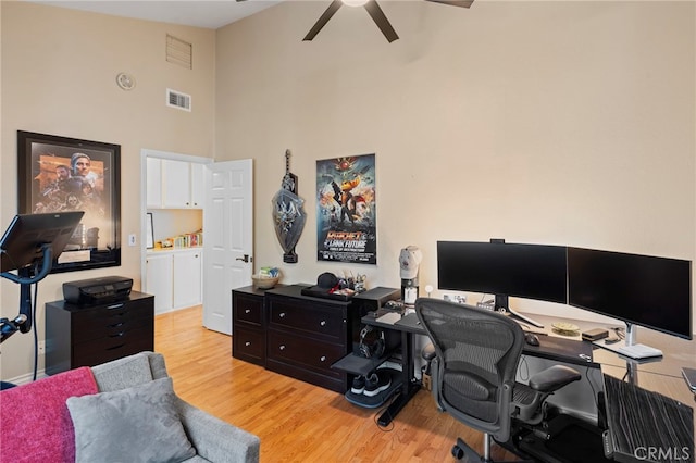 home office featuring a high ceiling, light wood-type flooring, and ceiling fan