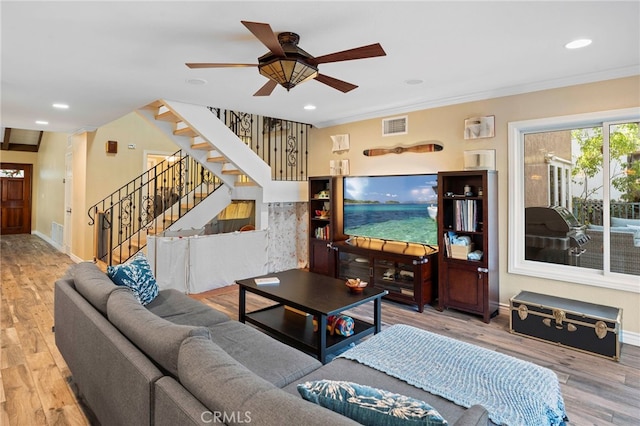 living room featuring wood-type flooring, ceiling fan, and crown molding