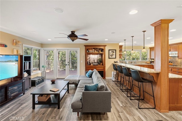 living room with decorative columns, french doors, ornamental molding, ceiling fan, and wood-type flooring