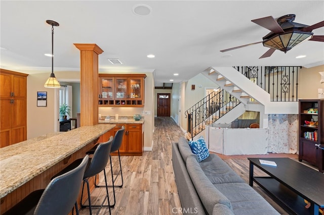 living room featuring ornamental molding, ceiling fan, and light wood-type flooring