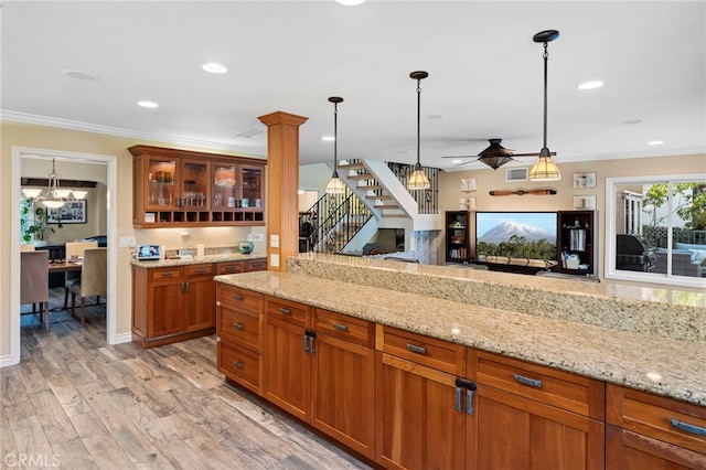 kitchen featuring light stone countertops, light hardwood / wood-style flooring, pendant lighting, crown molding, and ceiling fan