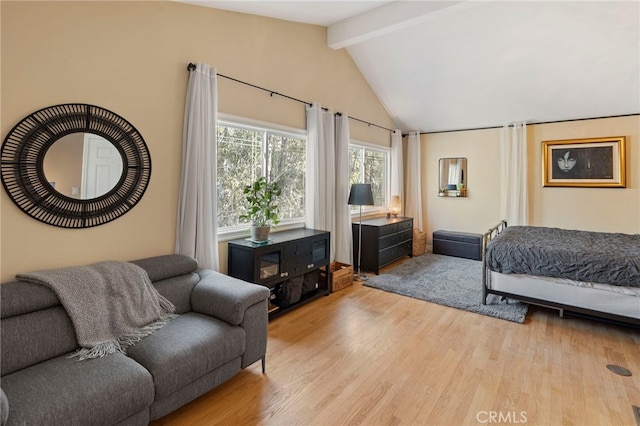 bedroom featuring light wood-type flooring and vaulted ceiling with beams