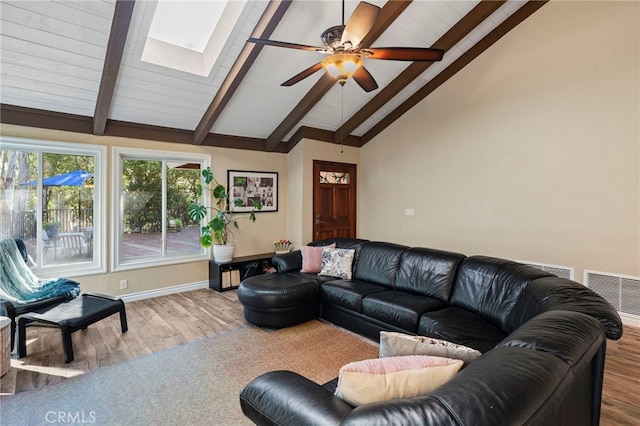 living room featuring ceiling fan, vaulted ceiling with skylight, and hardwood / wood-style floors