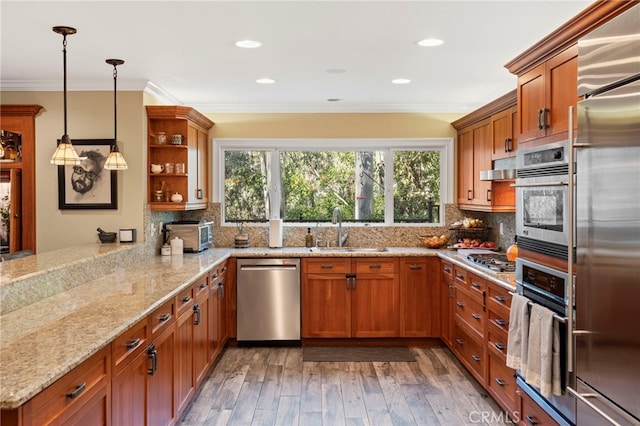 kitchen featuring stainless steel appliances, sink, hardwood / wood-style flooring, kitchen peninsula, and pendant lighting