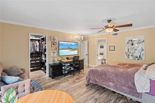 bedroom featuring light hardwood / wood-style flooring, ceiling fan with notable chandelier, a closet, a walk in closet, and crown molding