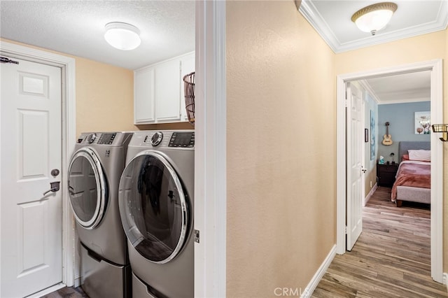 clothes washing area featuring separate washer and dryer, cabinets, ornamental molding, a textured ceiling, and light hardwood / wood-style flooring