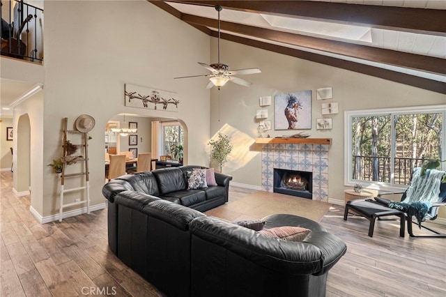 living room featuring a tiled fireplace, a healthy amount of sunlight, and beamed ceiling