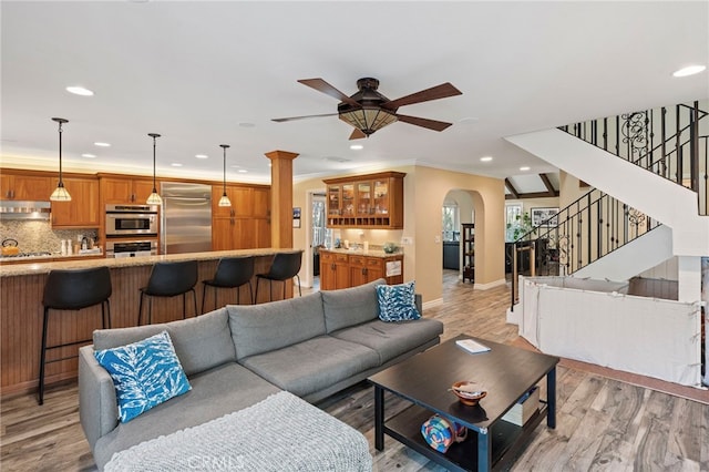 living room with ornamental molding, ceiling fan, and light hardwood / wood-style floors