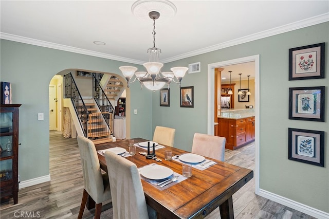 dining area featuring a notable chandelier, ornamental molding, and light hardwood / wood-style flooring