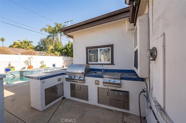 view of patio featuring sink, area for grilling, and a fenced in pool