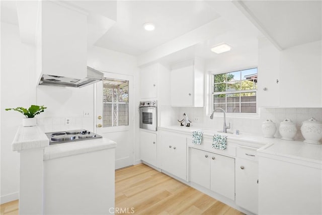 kitchen with white cabinets, light wood-type flooring, appliances with stainless steel finishes, and backsplash