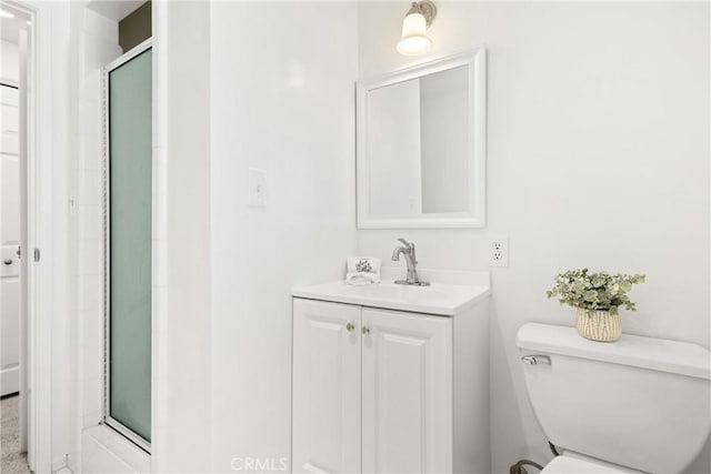 bathroom featuring toilet, a shower with door, and vanity