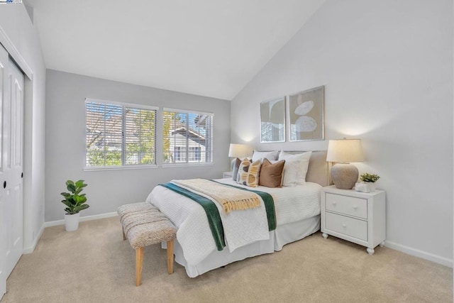 bedroom with vaulted ceiling, light colored carpet, and a closet