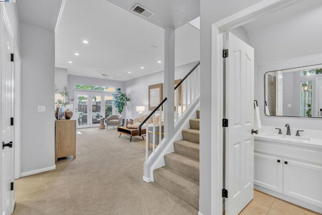 stairway with sink, french doors, and carpet flooring