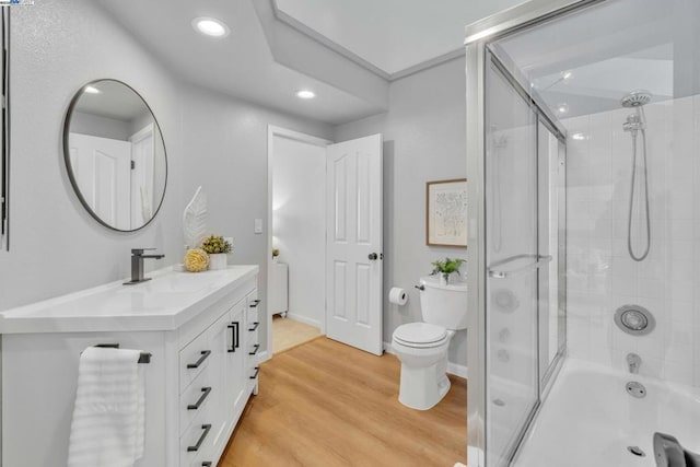 full bathroom with toilet, vanity, bath / shower combo with glass door, and hardwood / wood-style flooring