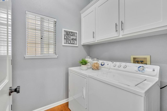 laundry room with cabinets, washing machine and clothes dryer, and light hardwood / wood-style floors