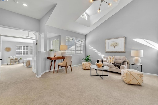 living room with ceiling fan with notable chandelier, high vaulted ceiling, and light carpet