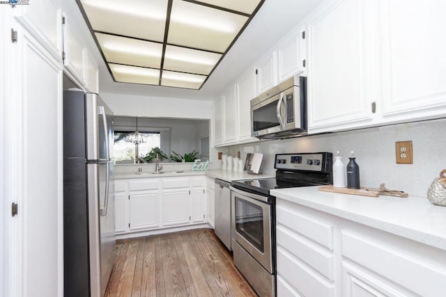 kitchen with sink, white cabinets, hardwood / wood-style floors, and appliances with stainless steel finishes