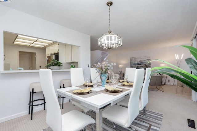 dining area with an inviting chandelier and light carpet