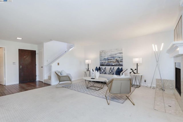 living room featuring wood-type flooring and a tiled fireplace