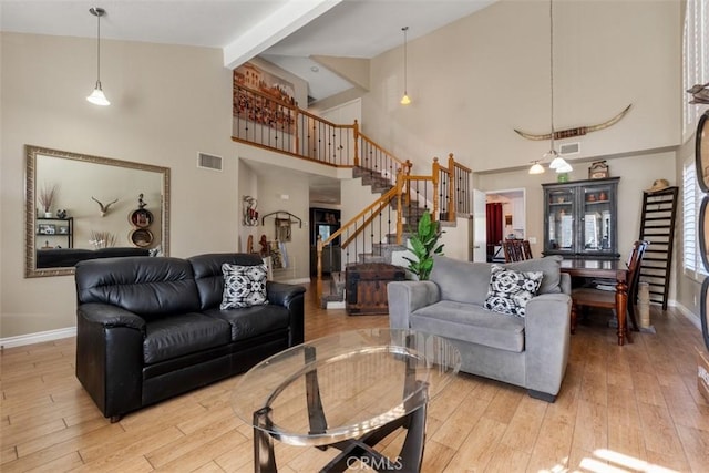 living room with light hardwood / wood-style floors, a chandelier, high vaulted ceiling, and beamed ceiling