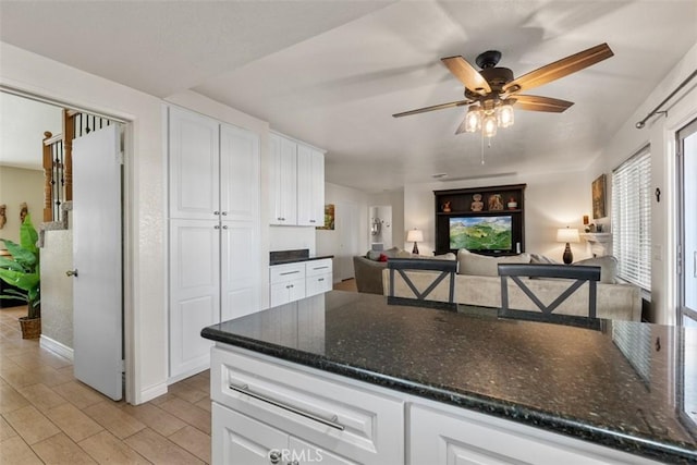 kitchen featuring dark stone countertops, white cabinetry, light wood-type flooring, and ceiling fan