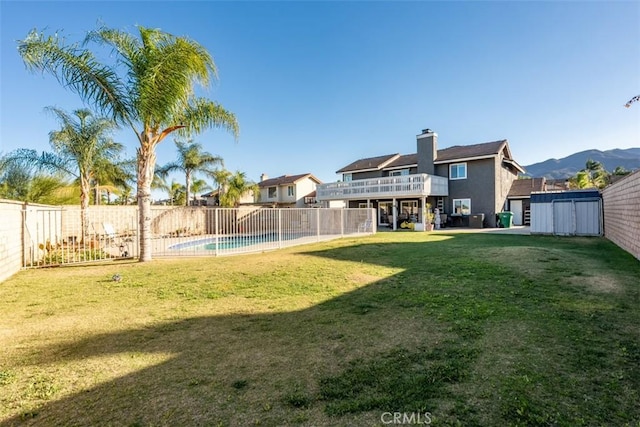 view of yard with a fenced in pool, a mountain view, and a storage shed