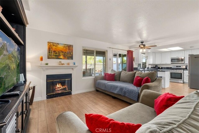 living room with light wood-type flooring and ceiling fan