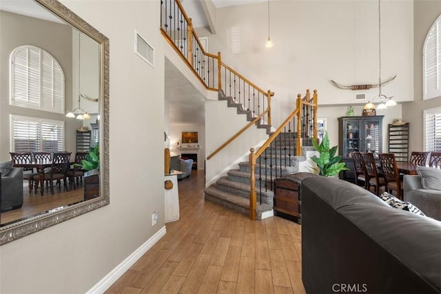 stairway with a high ceiling, a chandelier, and hardwood / wood-style floors