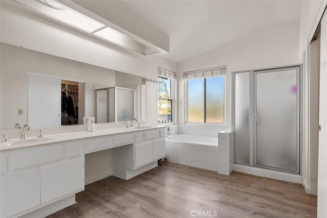 bathroom featuring wood-type flooring, vanity, vaulted ceiling, and plus walk in shower