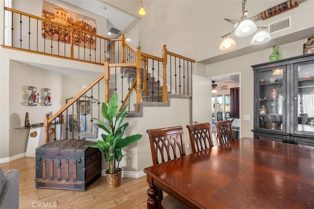 dining space with ceiling fan, a high ceiling, and wood-type flooring