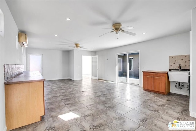 unfurnished living room with ceiling fan, a wall mounted air conditioner, and sink