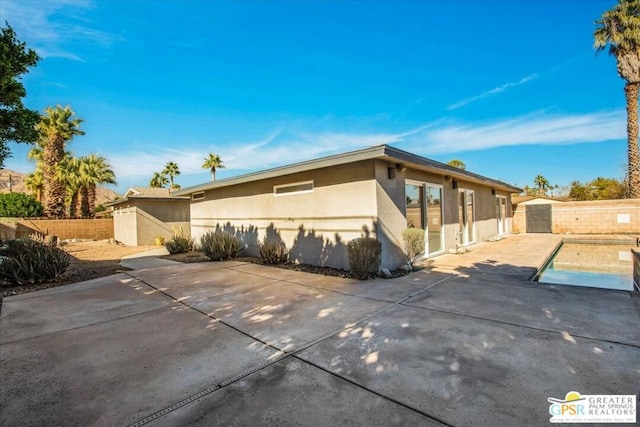 view of property exterior featuring a fenced in pool and a patio