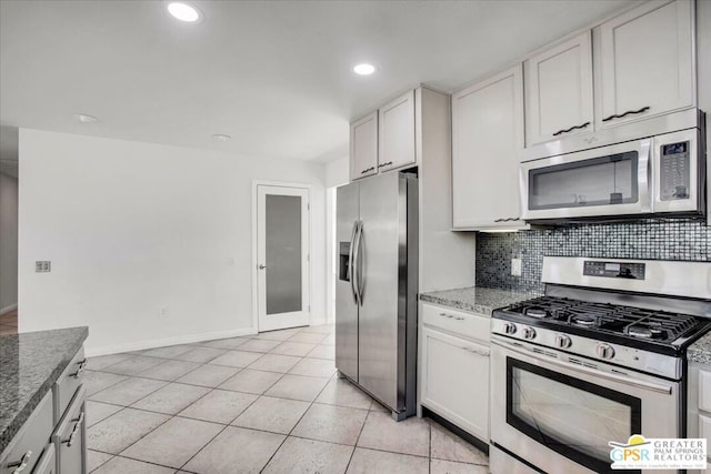 kitchen featuring stainless steel appliances, white cabinets, light tile patterned flooring, and stone counters