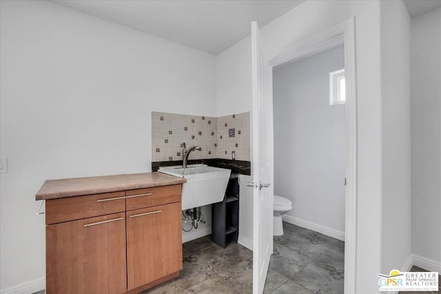 bathroom with toilet, tasteful backsplash, and sink