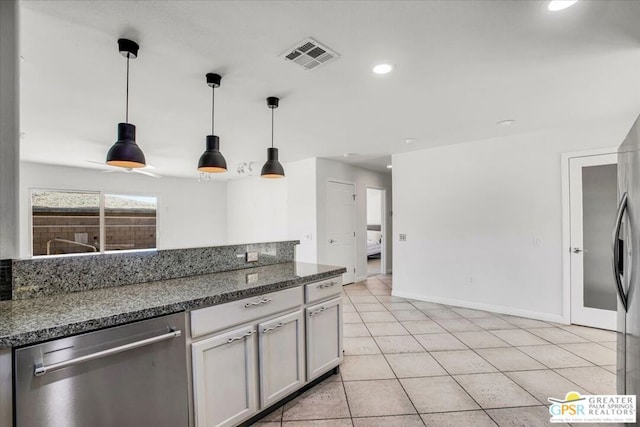 kitchen with stainless steel dishwasher, dark stone countertops, light tile patterned floors, and hanging light fixtures