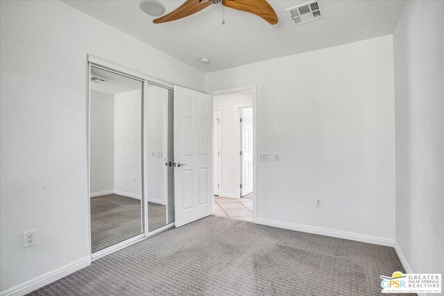 unfurnished bedroom with ceiling fan, light colored carpet, and a closet