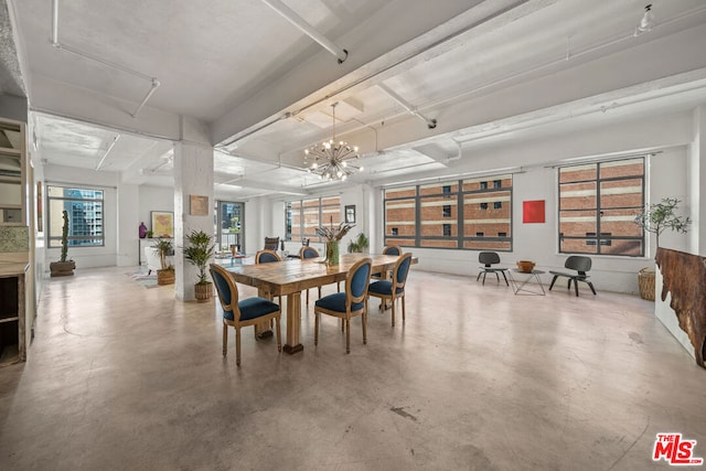 dining area with concrete floors and a notable chandelier