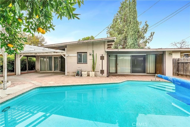 rear view of property with a pergola, a patio area, and a covered pool