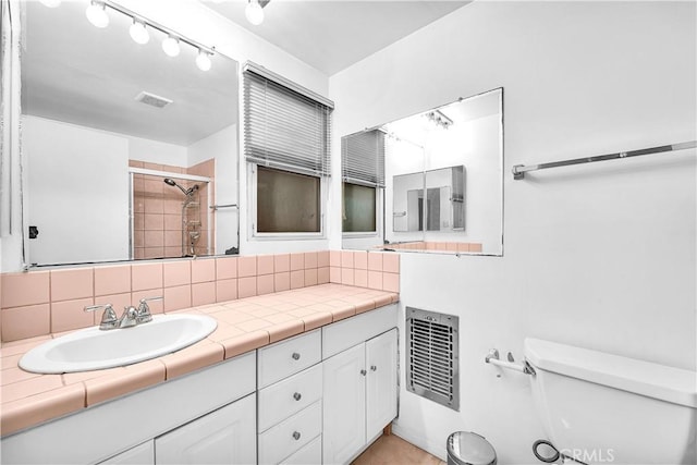 bathroom with vanity, backsplash, toilet, heating unit, and a tile shower