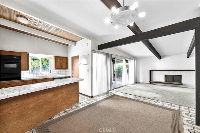 kitchen featuring a healthy amount of sunlight, backsplash, tile countertops, and vaulted ceiling with beams