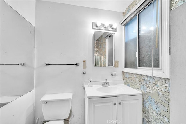 bathroom featuring toilet, vanity, and tasteful backsplash