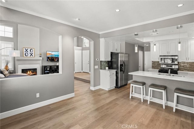 kitchen featuring stainless steel appliances, white cabinetry, a kitchen bar, and decorative backsplash