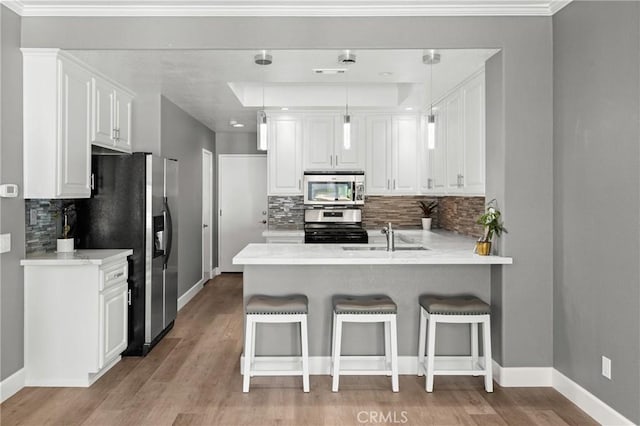 kitchen featuring stainless steel appliances, pendant lighting, a kitchen bar, sink, and white cabinetry