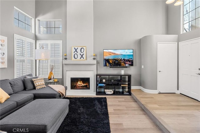 living room featuring a towering ceiling and light wood-type flooring