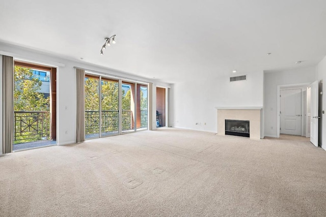 unfurnished living room with track lighting, light carpet, and a healthy amount of sunlight