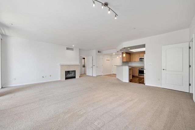 unfurnished living room featuring a tile fireplace and light colored carpet